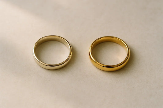 A paler 14K yellow gold wedding band beside a deeper 18K yellow gold band
