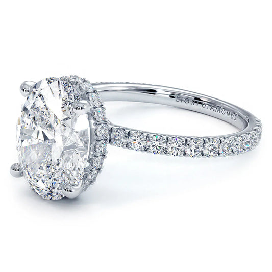 An oval-cut hidden halo engagement ring shown at an angle, with the under-stone diamonds visible from the side beneath the center stone.