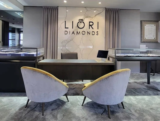The Liori Diamonds showroom at 580 Fifth Avenue, New York City, showing the marble LIORI DIAMONDS feature wall, lit jewelry display cases, and consultation seating.