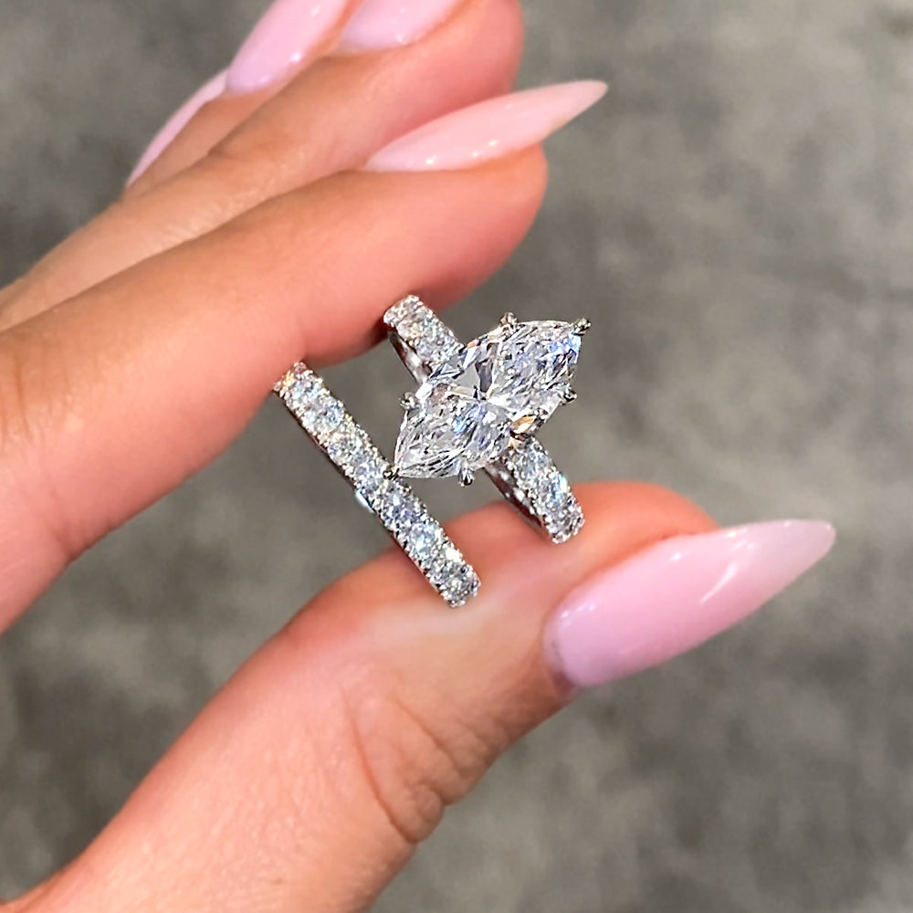 Close of Engagement Ring and Wedding Band held within fingers against a blurred background